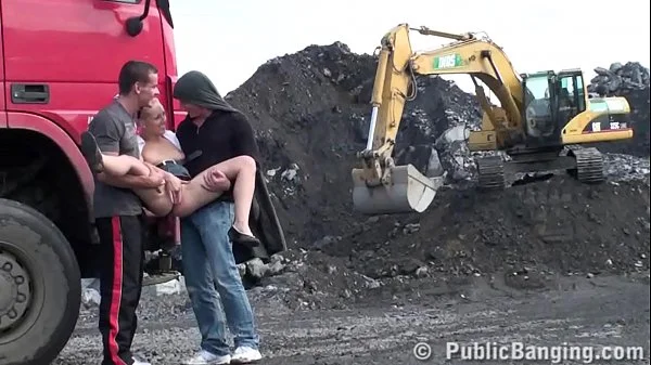 A very cute blonde young lady is fucked in public threesome at a construction site